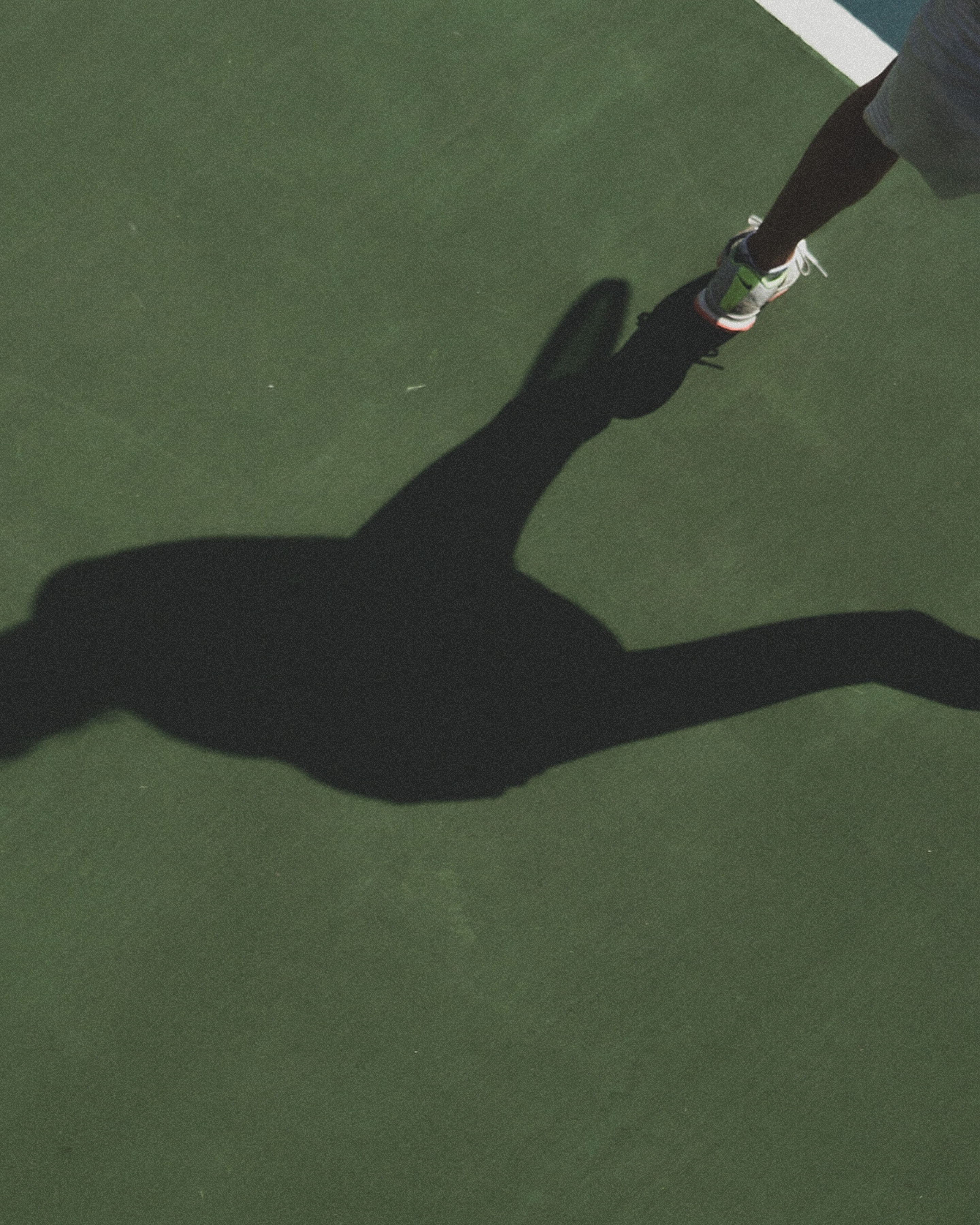 a player's shadow on the tennis court